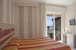um quarto de hotel com uma cama e uma varanda em Hotel Righetto Fronte Mare em Cavallino-Treporti