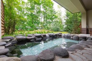 旭川的住宿－Morinoyu Hotel Hanakagura，庭院内一座带岩石的游泳池