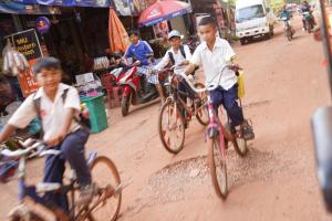 a group of children riding bikes down a street at DEN HOTEL TOTONOU SIEM REAP in Siem Reap