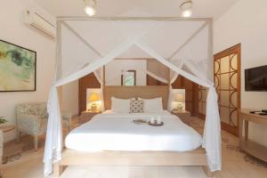 a bedroom with a white bed with a canopy at StayVista at Villa Arcadia with Alfresco Dining in Candolim +12 photos