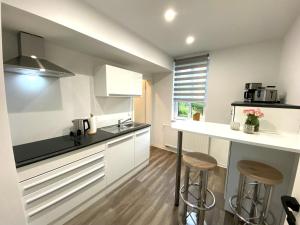 a kitchen with white cabinets and a counter with stools at Ferienwohnungen zur alten PuppenFabrik in Sonneberg