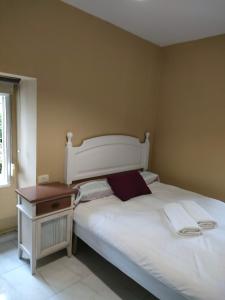 1 dormitorio con cama blanca y mesita de noche en pension mar de rosa en Villanueva de Arosa