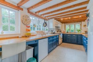 a large kitchen with blue cabinets and windows at Woodfields in Kineton