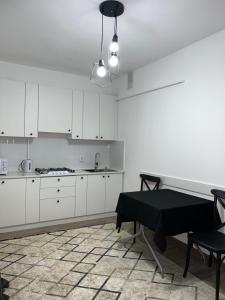 una cocina con armarios blancos y una mesa. en Милая и уютная однокомнатная квартира в г.Тараз en Taraz