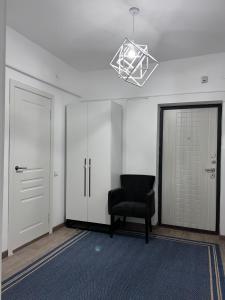 Habitación vacía con silla y lámpara de araña en Милая и уютная однокомнатная квартира в г.Тараз en Taraz