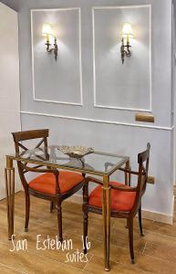 塞維利亞的住宿－SUITES SAN ESTEBAN 16 Real，一间设有玻璃桌和两把椅子的用餐室