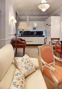 a living room with a couch and chairs and a kitchen at SUITES SAN ESTEBAN 16 Real in Seville +49 photos