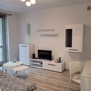 sala de estar blanca con cama y TV en Apartament Tuwima, en Zabrze