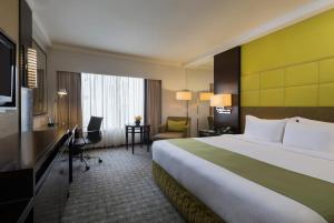 a hotel room with a large bed and a desk at Holiday Inn Singapore Orchard City Centre, an IHG Hotel in Singapore