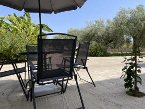 2 sedie sotto un ombrellone su un patio di La Casa del Gelsomino tra Noto e Mare a Noto Marina