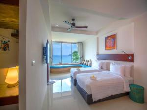 um quarto de hotel com duas camas e uma janela em Norn Talay Surin Beach Phuket em Praia de Surin