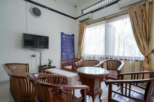 um quarto com uma mesa e cadeiras e uma televisão em RedDoorz @ Avros Guest House Medan em Medan