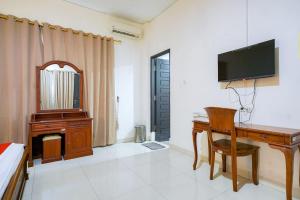 a room with a desk and a television and a bed at RedDoorz @ Avros Guest House Medan in Medan