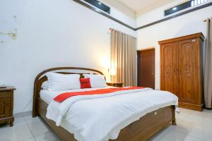 a bedroom with a large bed with a wooden headboard at RedDoorz @ Avros Guest House Medan in Medan