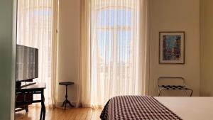 sypialnia z łóżkiem, telewizorem i oknem w obiekcie Casa do Bairro by Shiadu w Lizbonie