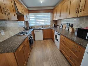 a kitchen with wooden cabinets and a washer and dryer at Piping House 4bedroom in Otterbourne