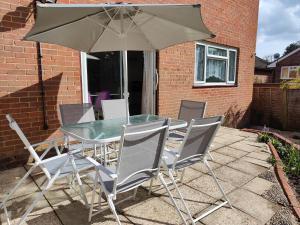 a table and chairs with an umbrella on a patio at Piping House 4bedroom in Otterbourne