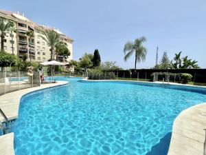 een groot blauw zwembad met palmbomen en gebouwen bij La Concha - EaW Homes in Marbella
