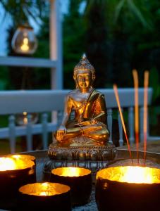 a statue of a buddha sitting next to candles at Buddhas Bed & Wellness - B&B - FEEL GOOD FOOD - kreativ - gesund - vegan 