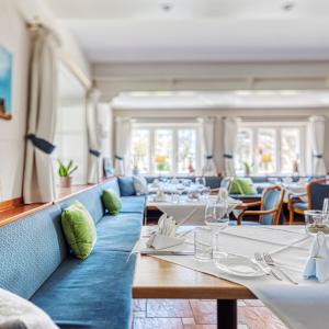 un restaurant avec des tables et des chaises blanches et des aorus dans l'établissement Fitschen am Dorfteich, à Wenningstedt