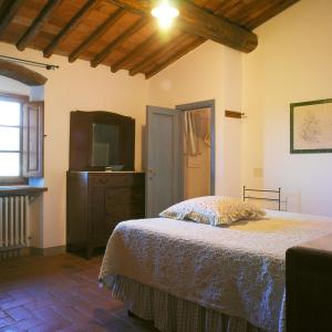a bedroom with a bed and a dresser and a television at Casa Ercole Farm Stay in Greve in Chianti