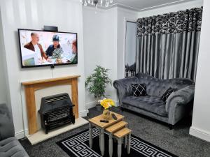 a living room with a couch and a tv on a wall at *12PR* Setup for your most relaxed & amazing stay + Free Parking + Free Fast WiFi * in Beeston Hill