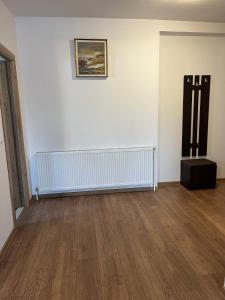 een witte kamer met een radiator en een houten vloer bij Casa Someseana in Gîlgău