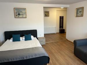 a bedroom with a bed with blue pillows and a couch at Casa Someseana in Gîlgău