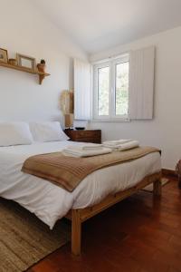 a bedroom with a bed with white sheets and a window at Casa da Maria • Natural Côte • Aljezur in Maria Vinagre