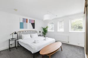 a white bedroom with a bed and a chair at Beachside Retreat 2-Bedroom Gem with FREE Private Parking & Outdoor Space in Brighton & Hove