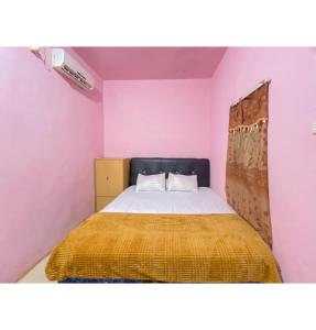 een slaapkamer met een bed met een gele deken bij Homestay Punokawan Puncak Indah Kota Malili Mitra RedDoorz in Malili
