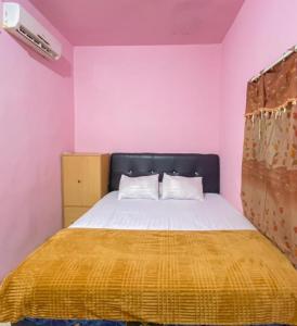 een slaapkamer met een bed met een gele deken bij Homestay Punokawan Puncak Indah Kota Malili Mitra RedDoorz in Malili