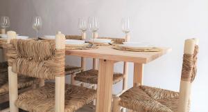 una mesa de madera con sillas, platos y copas de vino en Casa El Olmo de Navajas, en Navajas