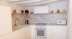 a white kitchen with a sink and a microwave at Casa El Olmo de Navajas in Navajas