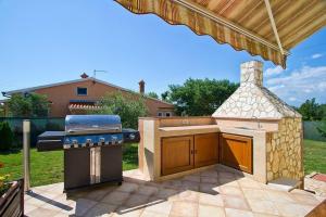 a outdoor kitchen with a grill in a backyard at Villa MAGGIE in Šišan