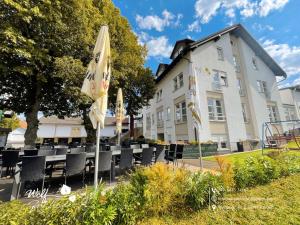 ein Hotel mit Stühlen und Sonnenschirmen vor einem Gebäude in der Unterkunft Wolf Hotel zur Linde in Künzell