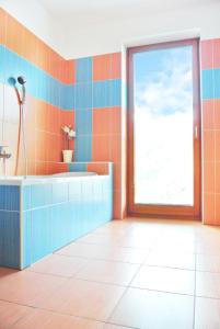 uma casa de banho laranja e azul com uma banheira e uma janela em Penzion Trnka em Potštejn