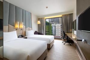 a hotel room with two beds and a desk and a television at Holiday Inn Express Bangkok Sukhumvit 11 by IHG in Bangkok