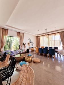 Villa Le Clos de l'Atlas في مراكش: غرفة معيشة كبيرة مع كراسي وطاولة