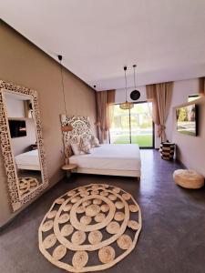 Villa Le Clos de l'Atlas في مراكش: غرفة نوم بسرير ومرآة كبيرة
