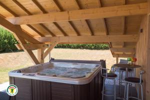 a hot tub under a wooden roof with stools under it at Le Val des Sens in Chatte