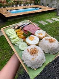 a person holding a tray of rice and vegetables at The Backyard Glamp - Book The Entire Campground 