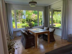 een eetkamer met een tafel, stoelen en ramen bij Idyllische Stadtwohnung im Grünen in Siegen