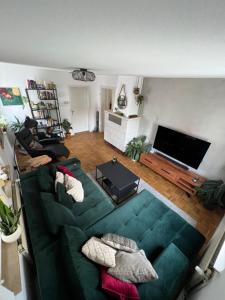 ein Wohnzimmer mit einem grünen Sofa und einem Flachbild-TV in der Unterkunft Zentrale 3 Zimmer Wohnung - Nähe Flughafen & Messe in Neuhausen auf den Fildern