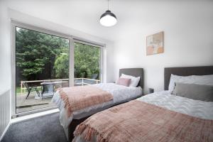- 2 lits dans une chambre avec une grande fenêtre dans l'établissement 3 Bedroom House Near Bolton Town Centre, Quiet, Parking, Garden, near Motorway, à Bolton