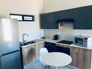 a small kitchen with a white stool and a microwave at Taina Apartment @ Green Creek in Pretoria