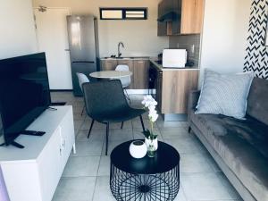 a living room with a couch and a table with flowers on it at Taina Apartment @ Green Creek in Pretoria