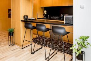 a kitchen with black stools at a counter at Rose Gold Apartment in Zalaegerszeg