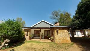 a house with a stone structure in the yard at Bluebell Barn in Dullstroom