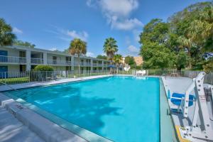 una piscina en un complejo con sillas y un edificio en Motel 6-Gainesville, FL, en Gainesville